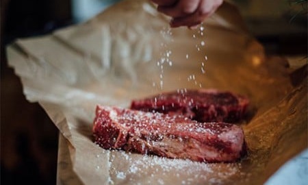 Seasoning steaks ready for the grill